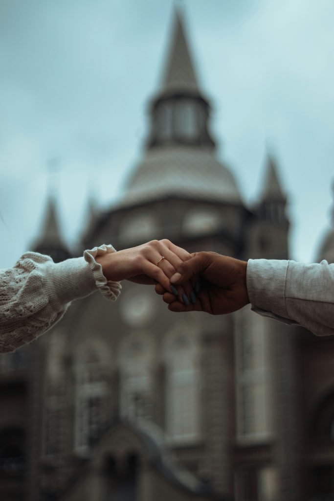 close-up shot of couple hands against the backdrop of a castle
