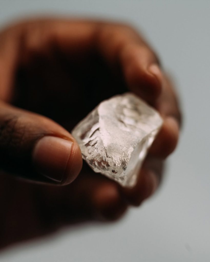 person holding a big rough diamond 