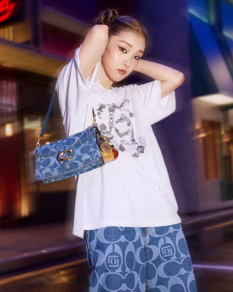 woman wearing a white graphic tee with jeans and denim bags