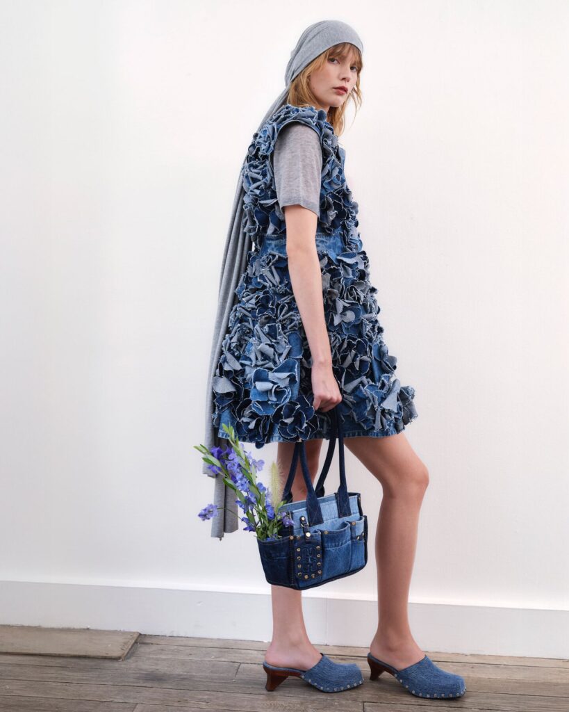 model wears a ruffled denim dress with denim bags and clogs for ganni