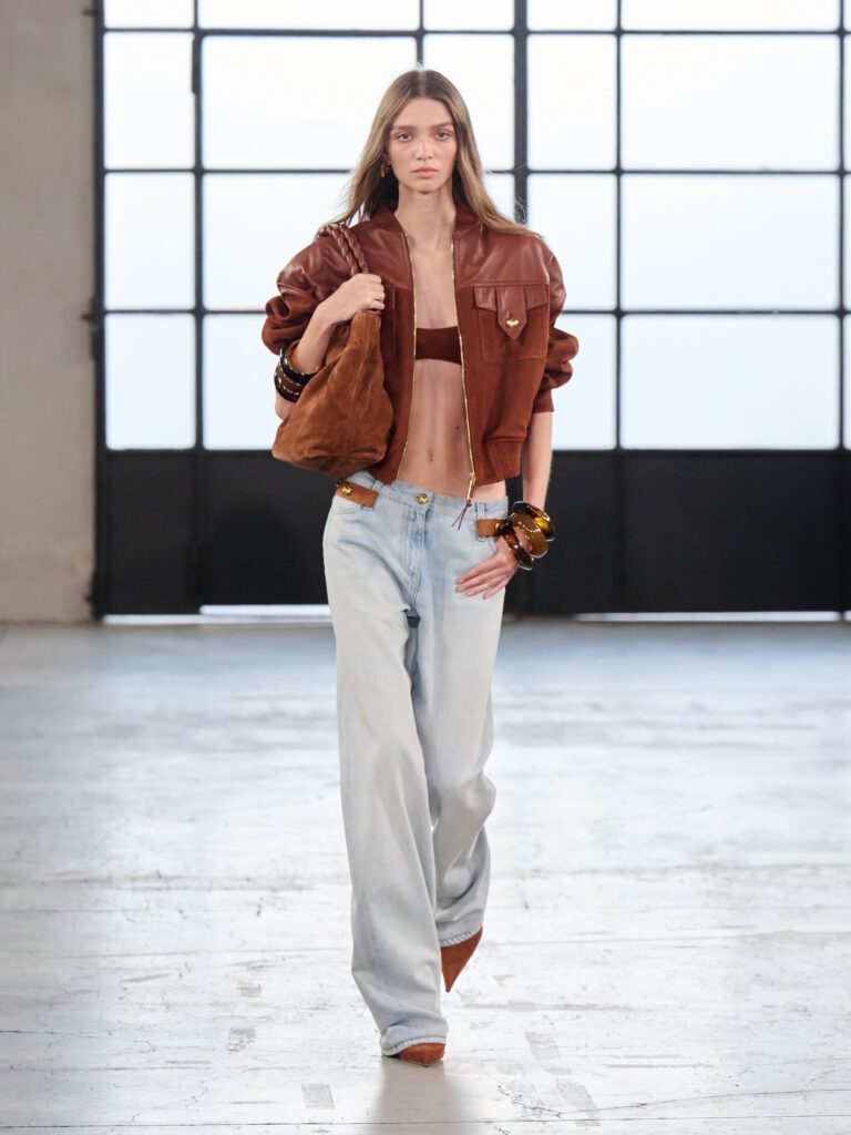 model wearing brown jacket and jeans with chunky bangles